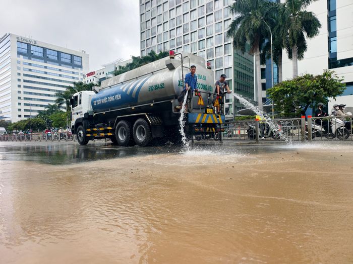 Xịt rửa bùn đất còn sót lại trên đường sau dọn dẹp. Ảnh: NGUYỄN TÂN