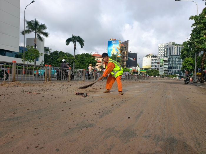 Công nhân vệ sinh xử lý lớp bùn đất trên đường. Ảnh: NGUYỄN TÂN
