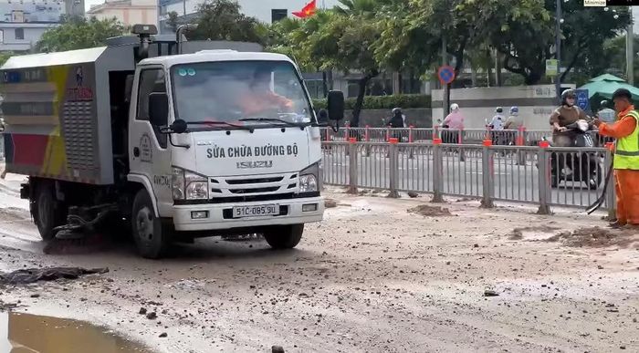 Công nhân thu gom bùn đất đổ trên đường