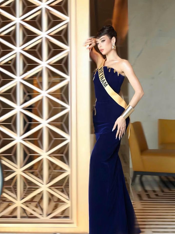 Đại diện Việt Nam tiếp tục lựa chọn phom váy ôm dáng nhưng thay đổi với sắc xanh đậm. Chi tiết ánh kim ở phần ngực cùng vòng tay bản lớn tạo điểm nhấn, trong khi tóc búi cao giúp tổng thể gọn gàng.