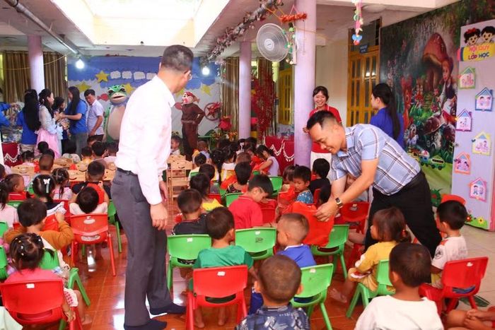 Nhà báo Nguyễn Minh Thịnh - Trưởng Văn phòng đại diện Báo Giáo dục và Thời đại khu vực Tây Bắc (bên phải) trao quà cho học sinh.