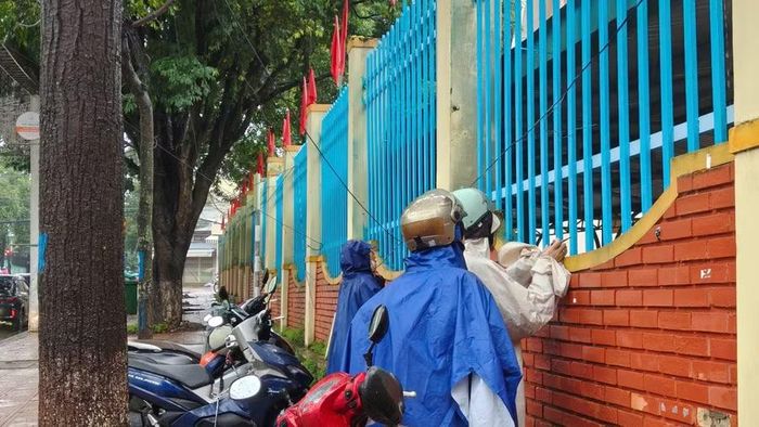 Các giáo viên đội mưa đến cổ vũ, động viên học sinh trước giờ làm bài.