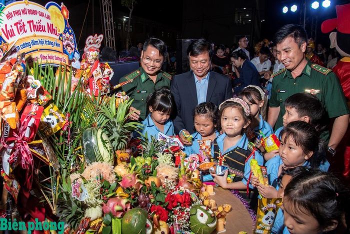 Đại tá Đoàn Ngọc Báu, Chính ủy Bộ đội Biên phòng tỉnh Gia Lai và đồng chí Nguyễn Tuấn Thanh, Phó Chủ tịch Thường trực Uỷ ban nhân dân tỉnh Gia Lai (từ trái sang) cùng các cháu thiếu nhi phá cỗ Trung thu. Ảnh: Lê Văn Chương
