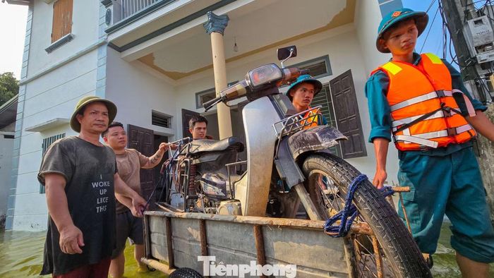 Lực lượng tại chỗ hỗ trợ người dân đưa xe máy và tài sản ra khỏi khu vực ngập sâu.