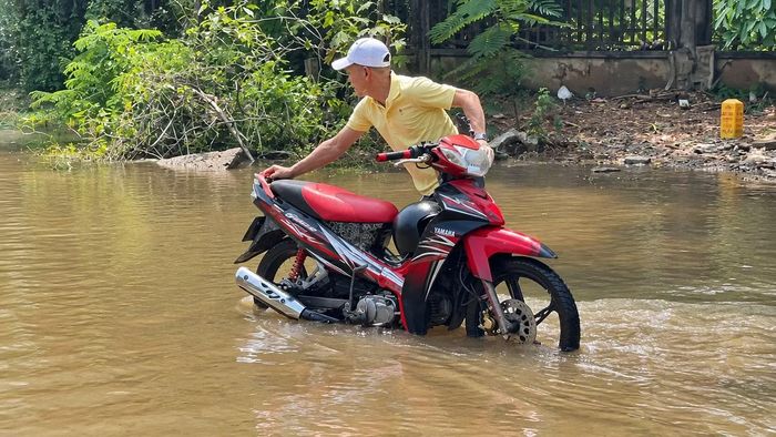 Cố băng qua những đoạn ngập nước quá nửa bánh xe trên Đại lộ Thăng Long, hàng loạt phương tiện lập tức bị chết máy, người dân phải chật vật dắt bộ giữa "biển" nước.