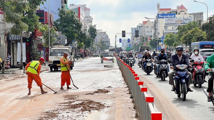 Công nhân vệ sinh mặt đường, xử lý bùn đất trên đường Cộng Hoà. Ảnh: Tuấn Kiệt
