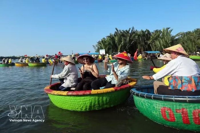 Du khách quốc tế thích thú khi trải nghiệm đi thuyền thúng truyền thống trên những kênh rạch rợp bóng dừa của làng Cẩm Thành, một trong 50 ngôi làng đẹp nhất thế giới năm 2025. (Ảnh: TTXVN)