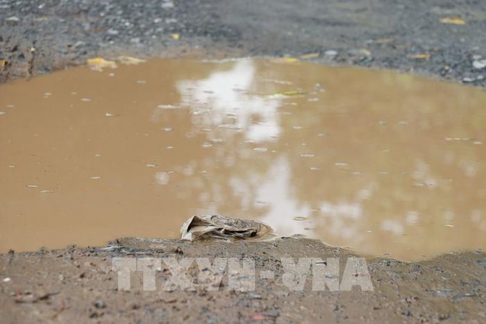 Nước mưa đọng vũng lớn trên mặt đường gây khó khăn trong việc đi lại của người dân. Ảnh: Hữu Chí - TTXVN
