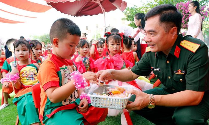  Đại tá Phương Nam Ký trao bánh, kẹo cho các cháu Trường Mầm non Phượng Sơn số 1. 