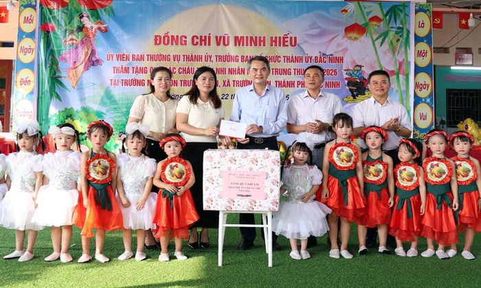 Đồng chí Vũ Minh Hiếu, Ủy viên Ban Thường vụ Thành ủy, Trưởng Ban Tổ chức Thành ủy cùng các đại biểu tặng quà cho thiếu nhi Trường Mầm non Trường Sơn.