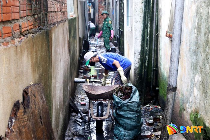 Các lực lượng chức năng phường Hải Châu ra quân thu gom rác thải sinh hoạt, khơi thông cống rãnh tại lối thoát hiểm chung cư Thuận Phước. Ảnh: HÀN NGUYÊN