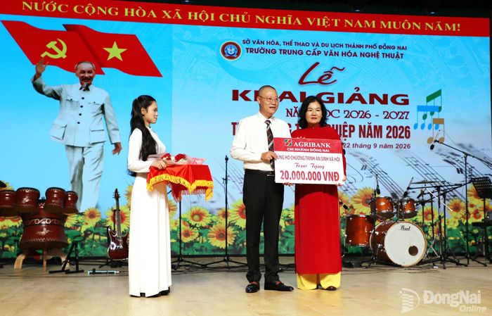 Đại diện Ngân hàng Nông nghiệp và Phát triển nông thôn (Agribank) chi nhánh Đồng Nai trao bảng tượng trưng các suất học bổng trị giá 20 triệu đồng cho lãnh đạo nhà trường. Ảnh: My Ny