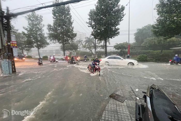 Tuyến đường Đồng Khởi ngập khiến người dân phải dắt xe vào lề chờ nước rút để di chuyển tiếp. Ảnh: Lê Duy