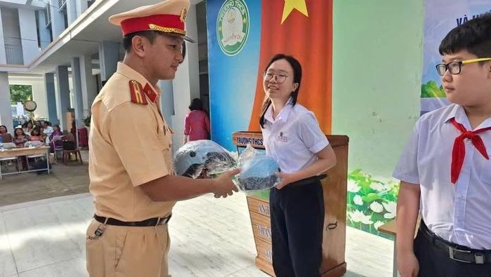 Lực lượng CSGT tặng mũ bảo hiểm cho các em học sinh tại buổi tuyên truyền. (Ảnh: Công an cung cấp).