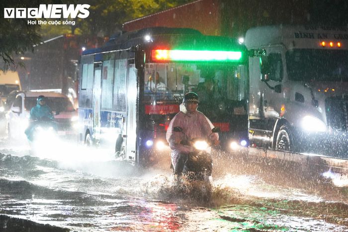 Nước ngập lênh láng khiến ranh giới giữa lòng đường và vỉa hè gần như không còn rõ, gây khó khăn cho người dân di chuyển.