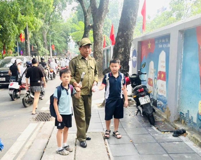 Lực lượng chức năng phường Kim Liên hỗ trợ đưa học sinh qua đường trên phố Hoàng Tích Trí. Ảnh: PV