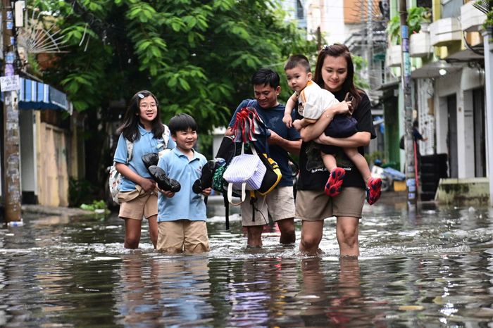 Cơn mưa lớn ngày 23/9 khiến đường phố TP.HCM ngập cục bộ. Phụ huynh phải lội nước đưa con đến trường. Ảnh: Hoài Bảo.