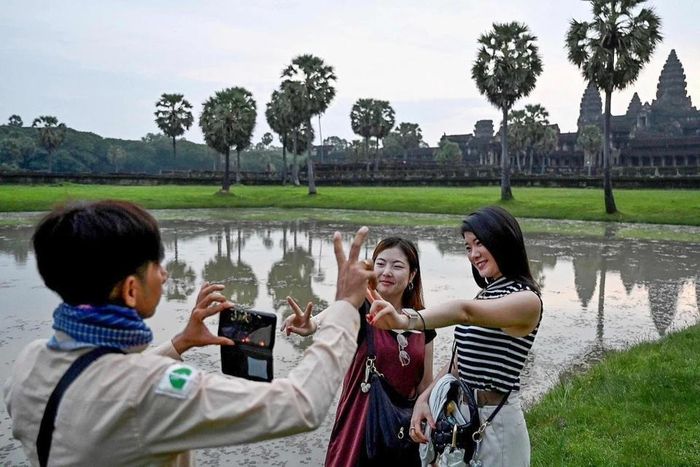  Hướng dẫn viên Campuchia giúp du khách Trung Quốc chụp ảnh tại quần thể đền Angkor Wat, tỉnh Siem Reap, năm 2024. Ảnh: CFP.