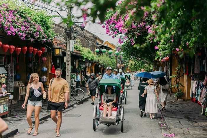 Khách quốc tế đi bộ và trải nghiệm xích lô giữa những giàn hoa giấy và dãy nhà cổ