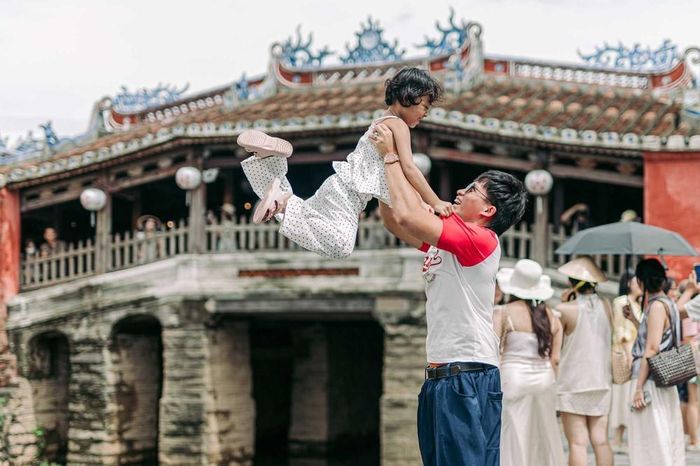 Khoảnh khắc vui đùa của hai cha con du khách trước Chùa Cầu