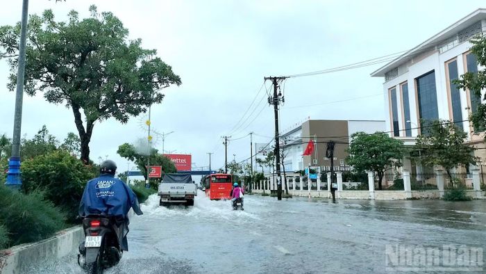 Phương tiện lưu thông khó khăn qua khu vực đường Trần Hưng Đạo (phường Tân Thành, tỉnh Cà Mau) do mặt đường bị ngập nước. (Ảnh: HỮU TÙNG)
