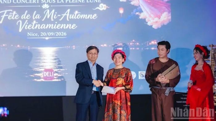 Ông Đinh Ngọc Đức, Giám đốc Trung tâm Văn hóa Việt Nam tại Pháp lên phát biểu và trao tặng quà cho bà Phùng Thảo Huyền, Trưởng Ban tổ chức chương trình, Chủ tịch Hội Cộng đồng người Việt Nam tại Nice.