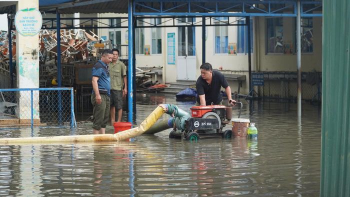 Nhân viên Trường Tiểu học Bình Triệu (phường Hiệp Bình, TPHCM) dùng máy bơm hút nước ngập vào sáng 23-9