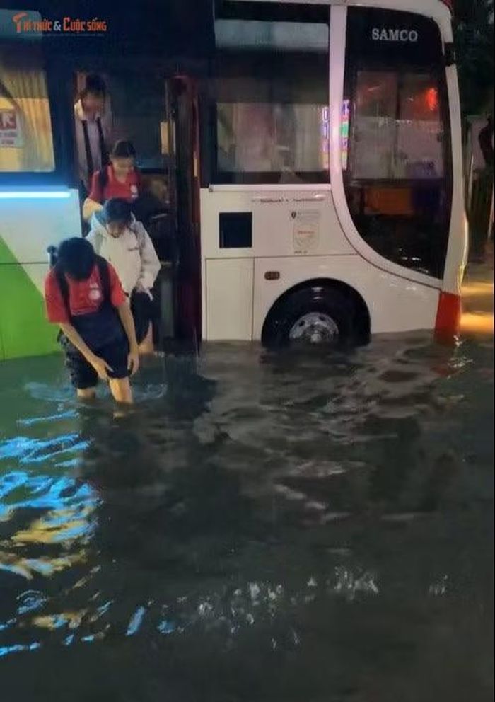 Học sinh phải lội trên đường ngập sau khi xuống từ xe ô tô đưa rước.