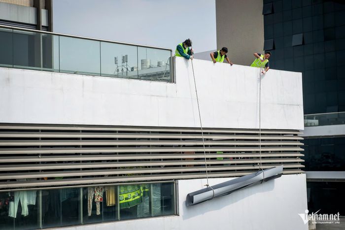 Công nhân vận chuyển tấm tôn lên mái nhà số 3, khu vực trên nóc Khoa Nội tiêu hóa để thi công lợp tôn chống thấm khe lún giữa các tòa nhà.