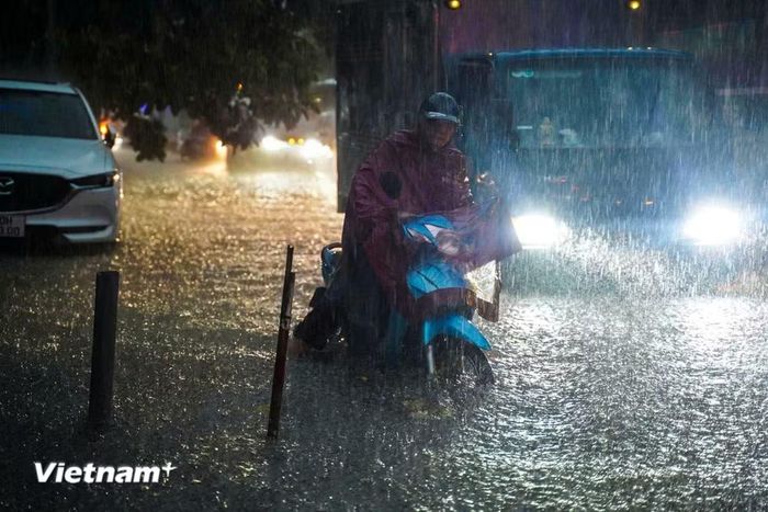 Người dân chật vật di chuyển qua các điểm ngập úng. (Ảnh: Hoài Nam/Vietnam+)