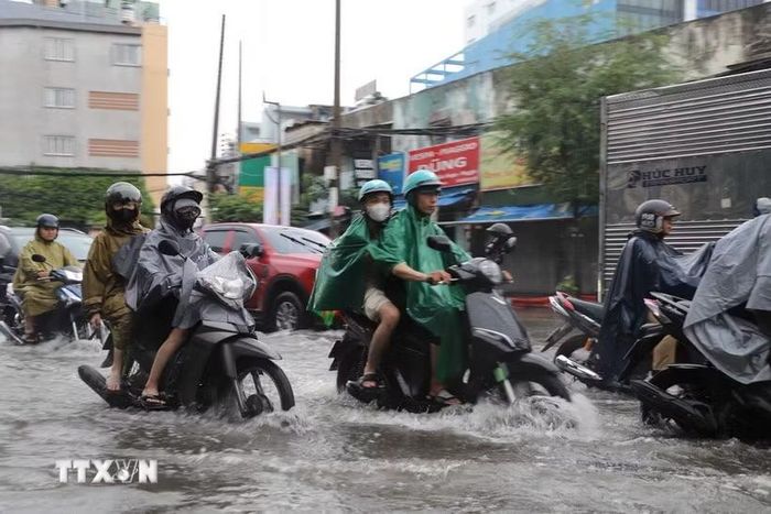 Người dân di chuyển qua đoạn đường Đinh Bộ Lĩnh, phường Bình Thạnh bị ngập do cơn mưa chiều 23/9. (Ảnh: Hồng Đạt/TTXVN)