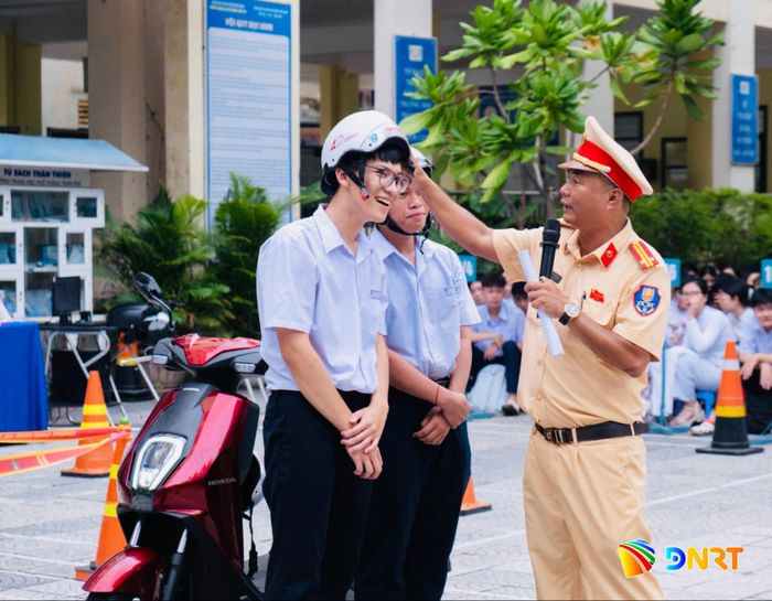 Cán bộ Cảnh sát giao thông hướng dẫn học sinh Trường THPT Hà Huy Tập (phường Tam Kỳ) đội mũ bảo hiểm đúng cách khi tham gia giao thông. Ảnh: ĐVCC