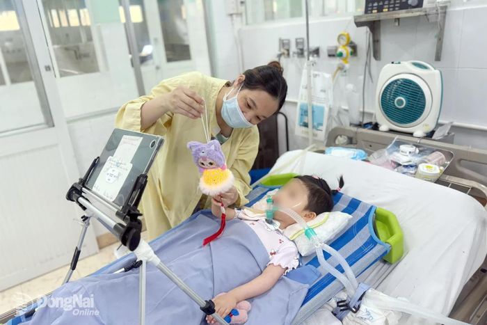 Chị Hằng cho con gái xem đèn Trung thu trên giường bệnh. Ảnh: Bích Nhàn 