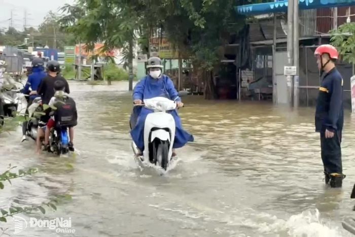 Lực lượng chức năng hỗ trợ điều tiết người dân vượt qua đoạn ngập tại xã Bình Minh. Ảnh: CTV