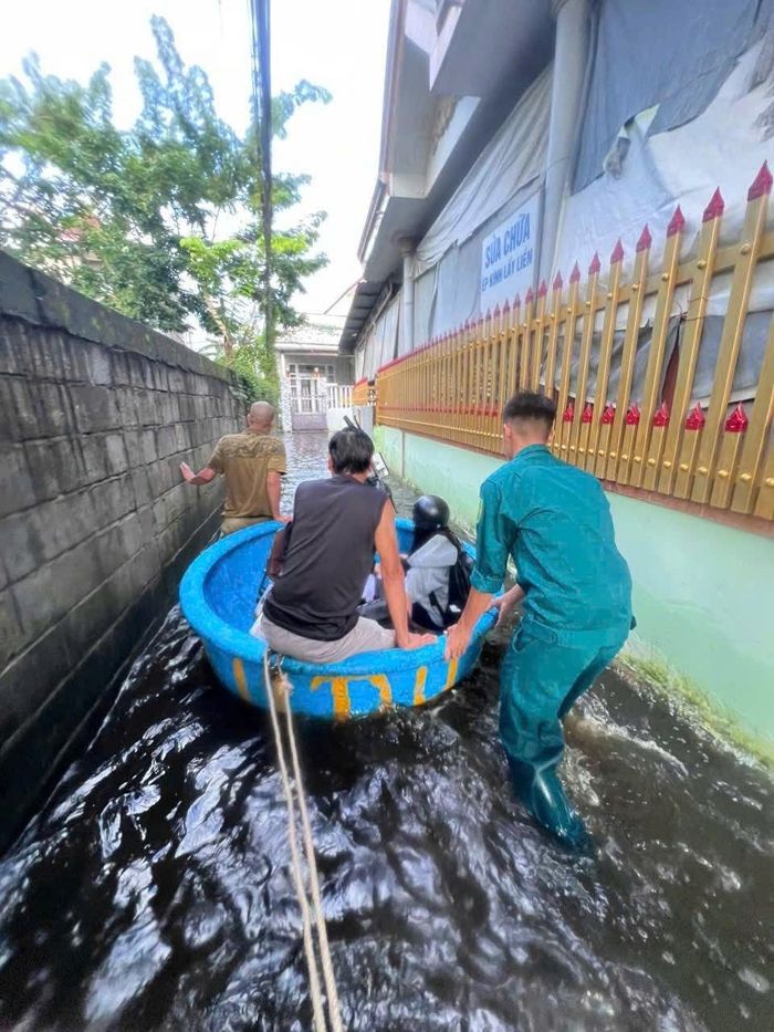 Lực lượng chức năng hỗ trợ người dân đi qua vùng bị ngập nước