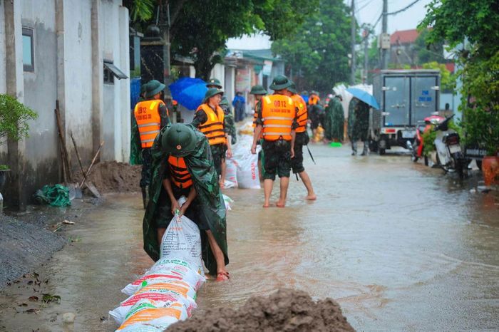  Lực lượng chức năng cùng nhân dân gia cố bờ kè, hạn chế nước tràn (Ảnh: MTTQVN) 