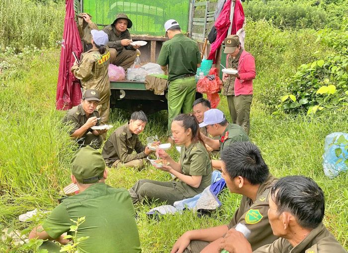 Cán bộ, chiến sĩ Công an xã Hòa Thịnh và lực lượng tham gia bảo vệ an ninh trật tự ở địa phương ăn trưa tại hiện trường để rút ngắn thời gian giúp dân thu hoạch sắn mì tránh mưa gây ngập úng.