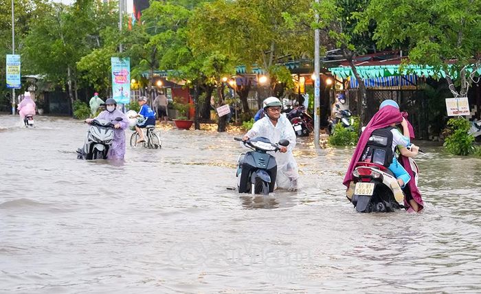 Nhiều người phải dẫn xe qua đoạn nước sâu; phụ huynh chở con đi học di chuyển khó khăn khi tránh các ổ gà dưới mặt nước.