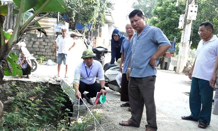 Cán bộ phòng Kinh tế xã Bình Minh cùng người dân thôn Cao Viên thực hiện đo và xác định diện tích đất mở đường. Ảnh T. Đạt