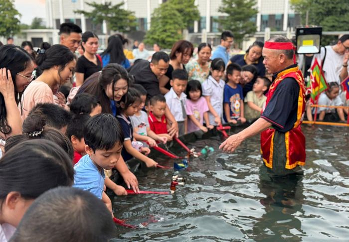 Các em thiếu nhi háo hức thưởng thức nghệ thuật múa rối nước và trực tiếp trải nghiệm điều khiển các con rối nước. Ảnh: TT
