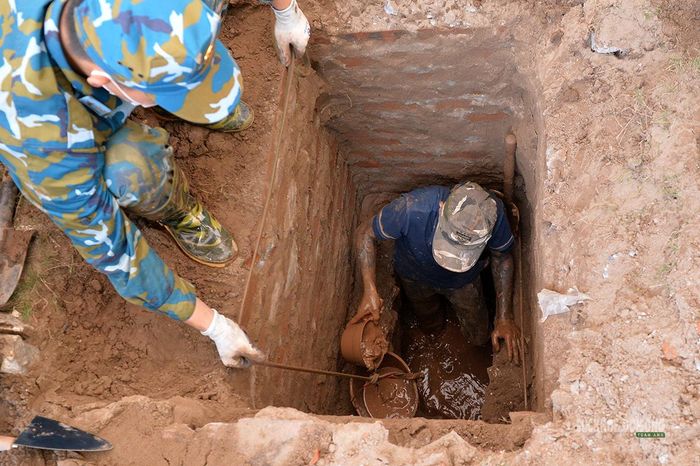 Nước và bùn đất gây khó khăn tại một phần mộ nằm sâu. Ảnh: Tuấn Anh