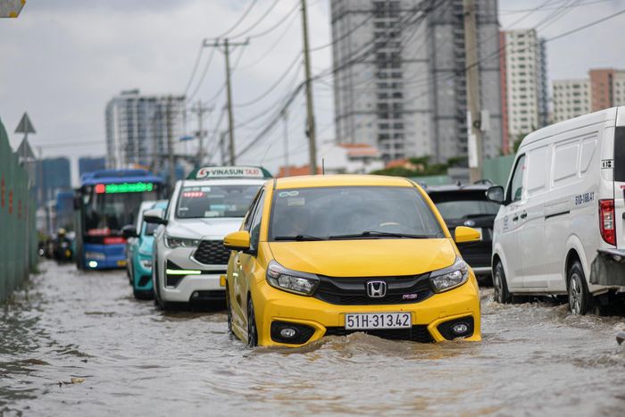 Nước ngập gần nửa bánh xe khiến các phương tiện di chuyển chậm, nối đuôi nhau kéo dài trên tuyến đường. Nhiều tài xế ôtô phải di chuyển chậm, đều qua đoạn ngập để hạn chế nước dâng, bắn vào khoang động cơ.