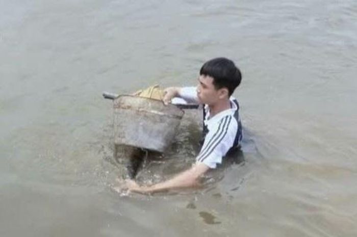 Hùng lao xuống nước đưa hai em nhỏ cùng chiếc xe đạp lên bờ.