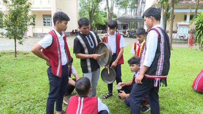 Nghệ nhân A Thu hướng dẫn các em học sinh cách chỉnh chiêng và cách đánh cồng chiêng