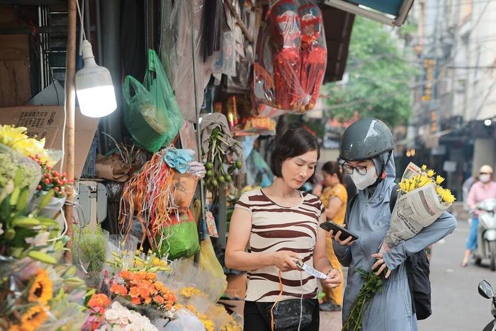 Tiểu thương linh hoạt áp dụng thanh toán QR code, phục vụ khách hàng thuận tiện hơn tại một số khu chợ ở Hà Nội. Ảnh: Lê Đông - TTXVN