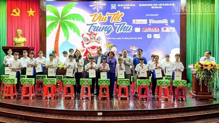 Đồng chí Đặng Thị Ngọc Thịnh, nguyên Ủy viên Trung ương Đảng, nguyên Phó Chủ tịch nước cùng nhà tài trợ trao quà cho các em thiếu nhi. (Ảnh: BÁ DŨNG)
