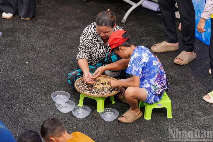 Ở một không gian khác, người dân hào hứng tham gia các trò chơi dân gian. Trong ảnh, các em nhỏ thích thú với trò chơi lựa đậu.
