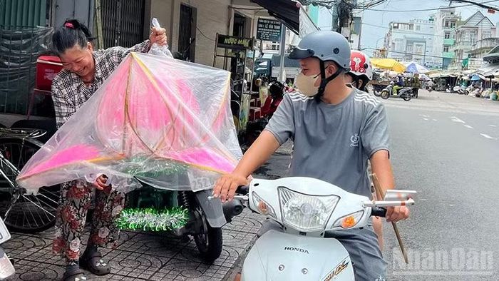 Bà Nguyễn Thị Ngọc Ngân giao lồng đèn Trung thu cho khách. (Ảnh: HỮU NGHĨA)