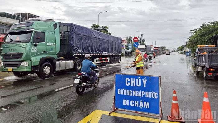 Lực lượng chức năng tổ chức chốt chặn, phân luồng bảo đảm an toàn cho người và phương tiện qua khu vực ngập sâu trên Quốc lộ 1A, đoạn qua trung tâm phường Hàm Thắng. (Ảnh: BẢO VĂN)