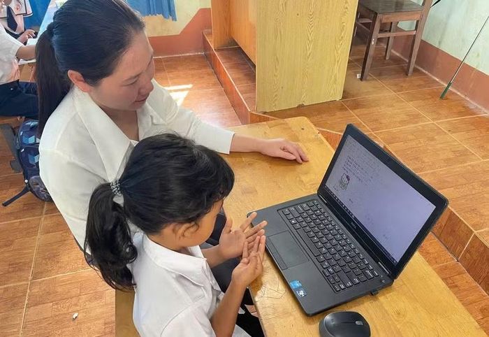 Giáo viên phân hiệu Trường Tiểu học Đinh Tiên Hoàng hỗ trợ các em làm quen và thực hành trong môi trường số bằng máy tính cá nhân. Ảnh: Thế Hùng